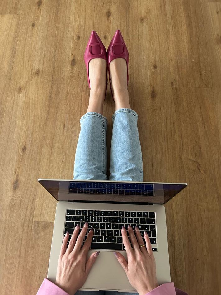 Bild aus der Vogelperspektive: Eva Beksa sitzt auf dem Boden und schreibt auf dem Laptop.